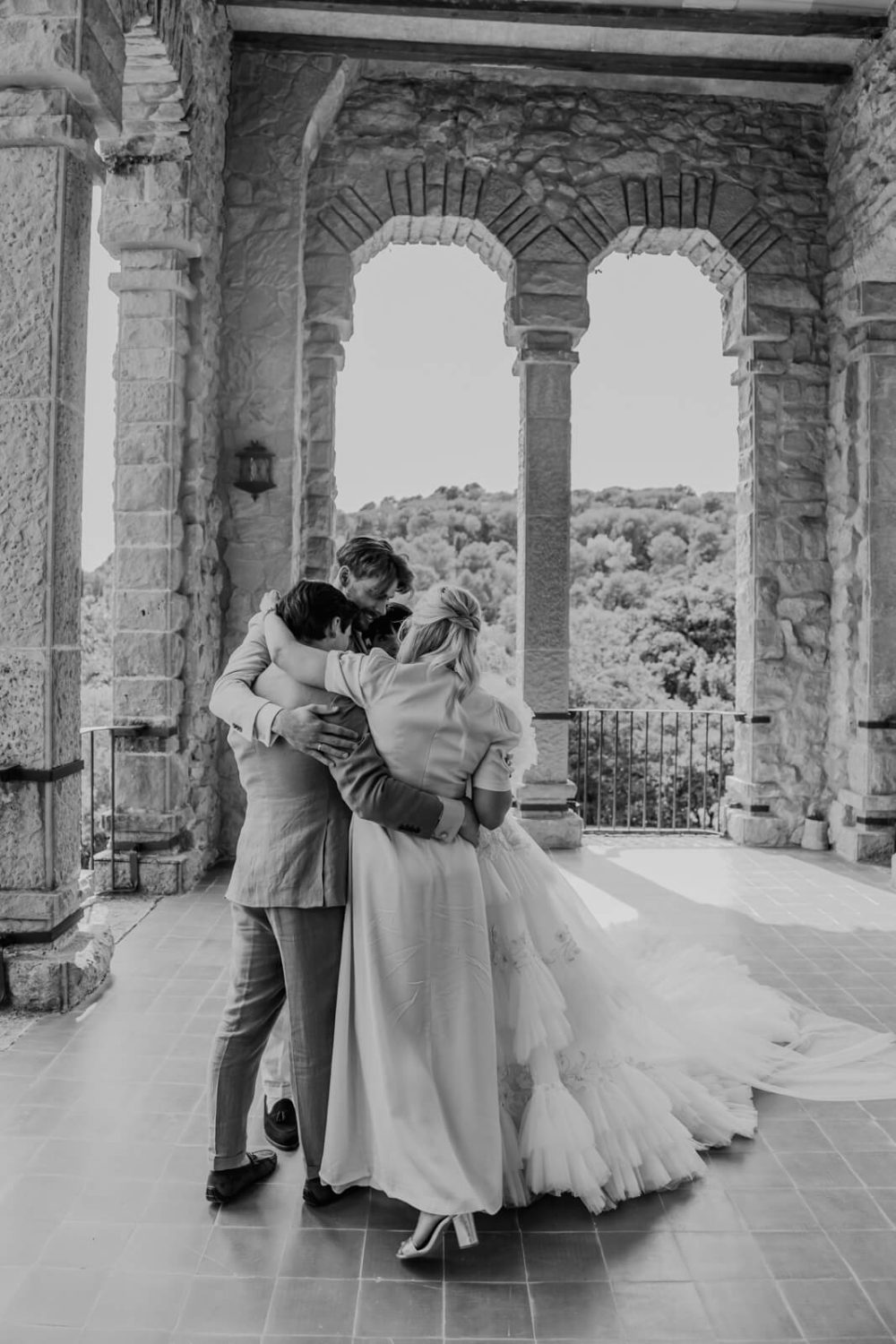 Black and white photograph of a couple embracing beneath stone arches