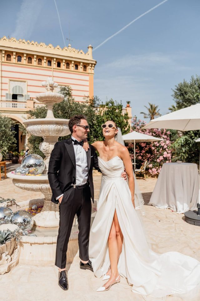 Bride and groom laughing beside a fountain at a Barcelona venue